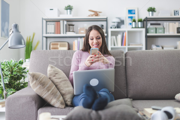 Nő sms chat okostelefon mosolyog fiatal nő otthon Stock fotó © stokkete