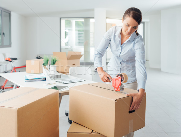 Businesswoman taping up a cardboard box Stock photo © stokkete