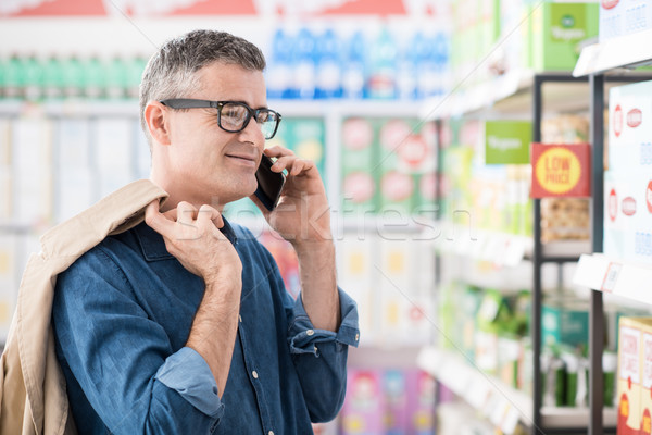 Man telefoongesprek supermarkt zoeken producten plank Stockfoto © stokkete