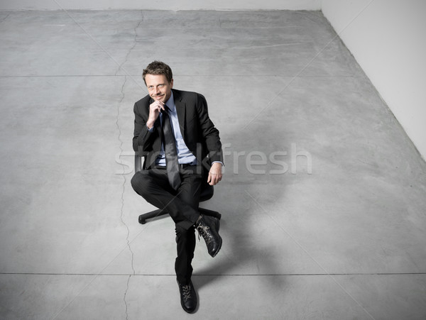 Biznesmen posiedzenia krzesło biurowe uśmiechnięty strony podbródek Zdjęcia stock © stokkete
