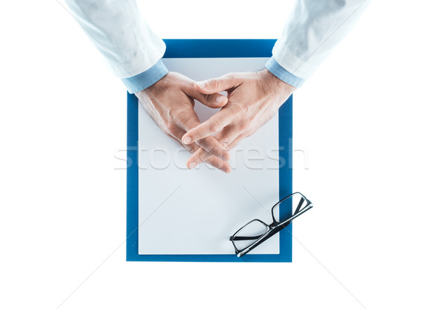 Doctor with hands clasped waiting at desk Stock photo © stokkete