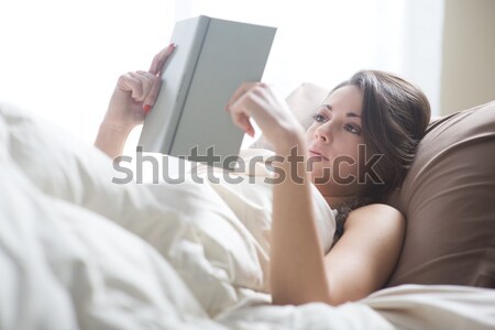 Woman enjoying with a digital tablet in bed in the morning, waking up. Stock photo © stokkete
