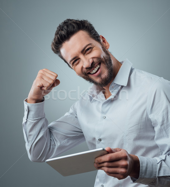 Derűs mosolyog fiatalember tabletta férfi jó hírek Stock fotó © stokkete