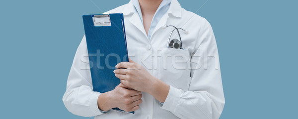 Professional female doctor posing with a clipboard Stock photo © stokkete