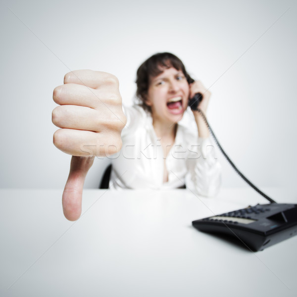 thumbs down against the camera by an hostile phoning businesswom Stock photo © stokkete
