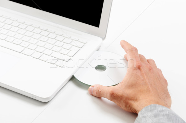Businessman inserting a cd on white laptop Stock photo © stokkete