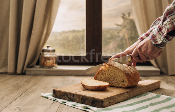 Mann Schneiden Laib frischen Brot Fenster Stock foto © stokkete