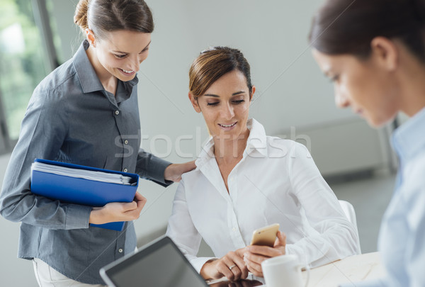 Femminile impiegati ufficio parlando guardare cellulare Foto d'archivio © stokkete