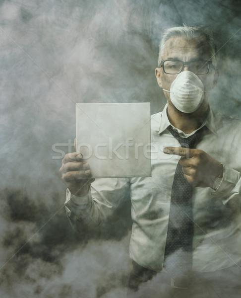 Businessman holding a sign and air pollution Stock photo © stokkete