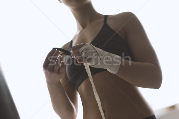 Boxer woman wrapping her wrists with protective bandage Stock photo © stokkete