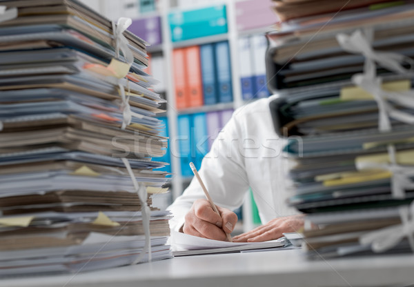 Businessman working in the office and piles of paperwork Stock photo © stokkete