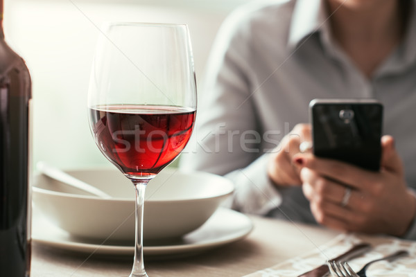 女子 智能手機 餐廳 飲用水 紅葡萄酒 精緻的餐點 商業照片 © stokkete