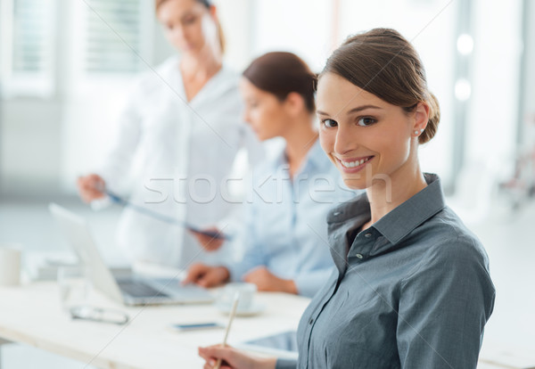 Foto stock: Sonriendo · mujer · de · negocios · posando · mirando · cámara · los · trabajadores · de · oficina