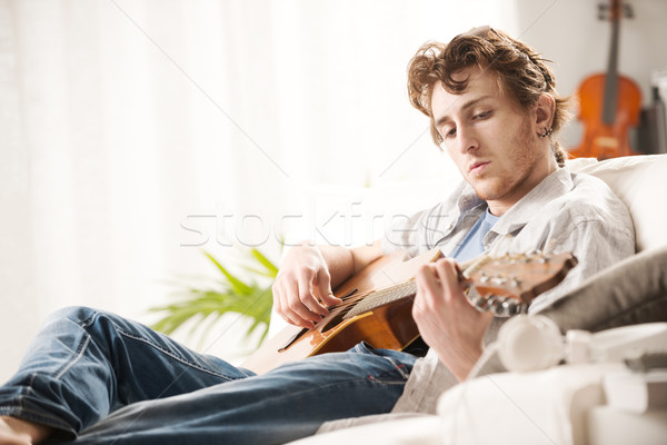 Lied jonge man spelen gitaar vergadering sofa Stockfoto © stokkete