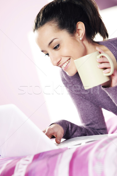 Happy casual  young lady using laptop while lying in bed Stock photo © stokkete