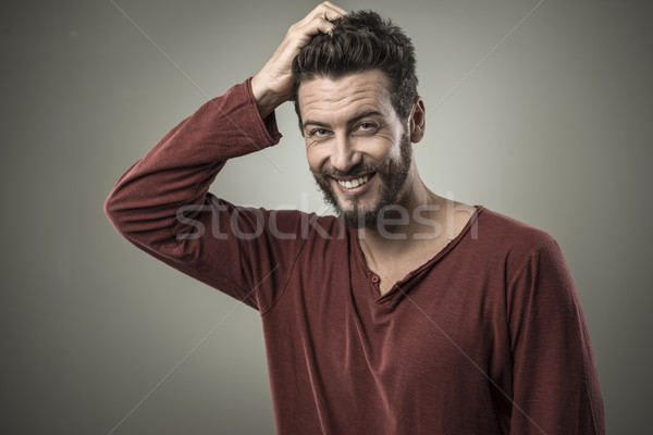 Kétséges fiatalember gondolkodik mosolyog megérint fej Stock fotó © stokkete