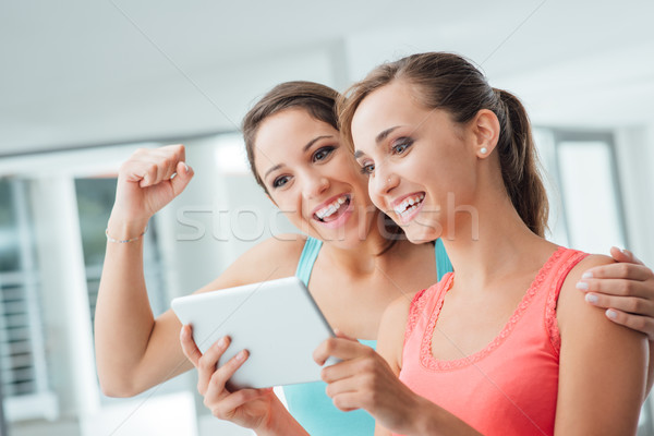 Happy girlfriends using a tablet Stock photo © stokkete