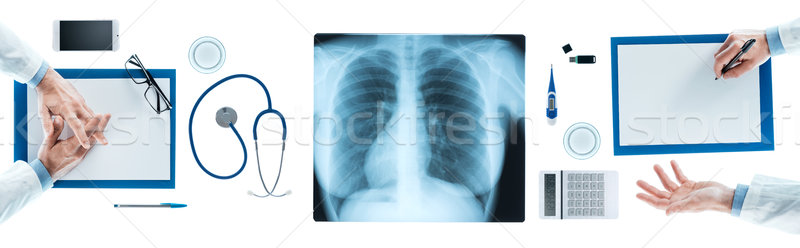 Medical team discussing during a briefing, x-ray image at center, top view, unrecognizable people Stock photo © stokkete