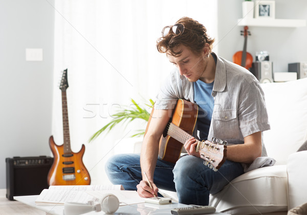 Chanson jeune homme jouer guitare séance canapé [[stock_photo]] © stokkete