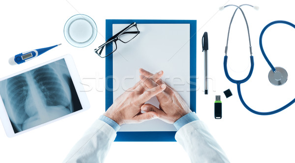 Doctor with hands clasped waiting at desk Stock photo © stokkete