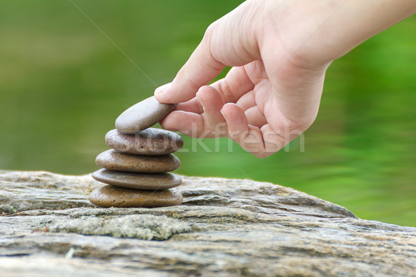 Hand put stone building a pile of zen stones Stock photo © stoonn