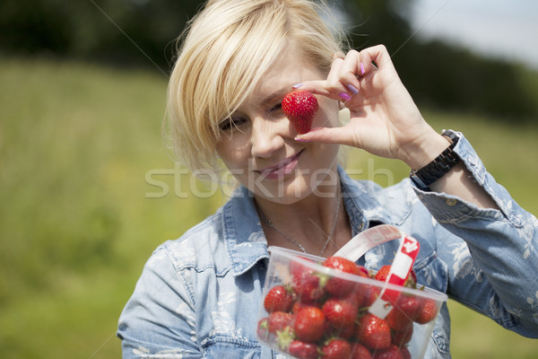 Woman holding up large ripe strawberry Stock photo © stryjek