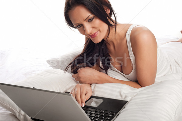 Femeie zambitoare folosind laptop pat zâmbitor frumos tineri Imagine de stoc © stryjek