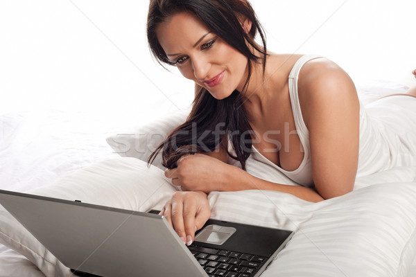 Foto stock: Sorrindo · usando · laptop · cama · sorridente · belo · jovem