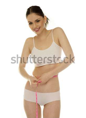 Beautiful young woman measuring her waistline Stock photo © stryjek