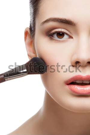 Beautiful girl applying blush with brush Stock photo © svetography