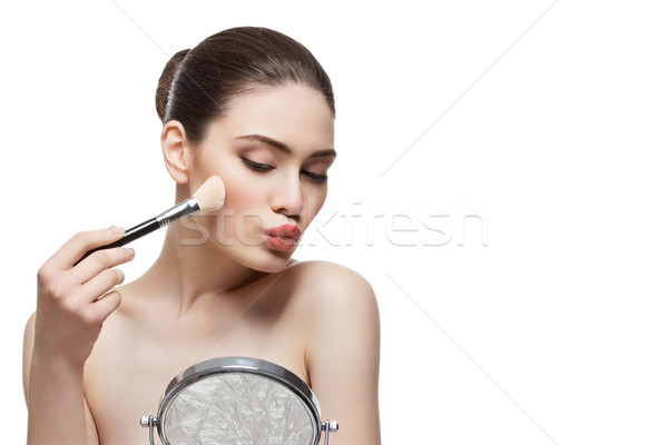 Beautiful girl applying blush with brush Stock photo © svetography