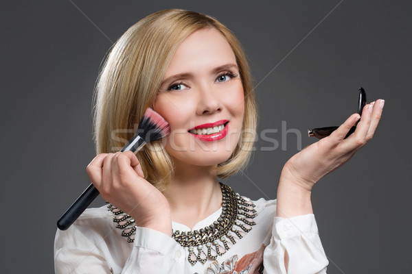 Beautiful middle aged woman applying blush Stock photo © svetography