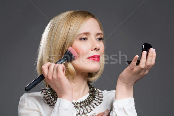 Beautiful middle aged woman applying blush Stock photo © svetography