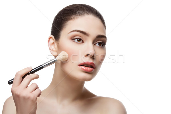 Beautiful girl applying blush with brush Stock photo © svetography