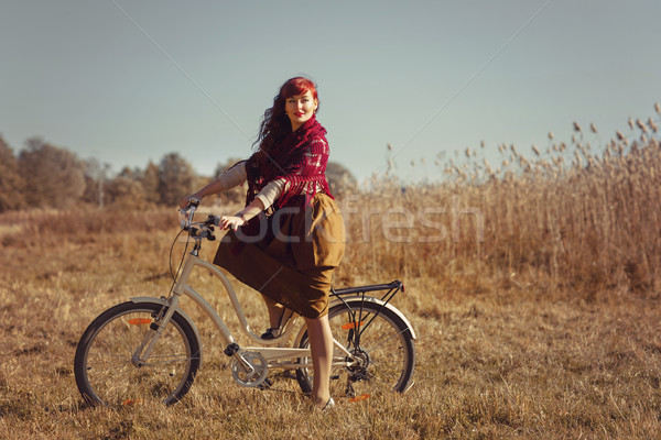 Pretty girl riding bicycle in field Stock photo © svetography