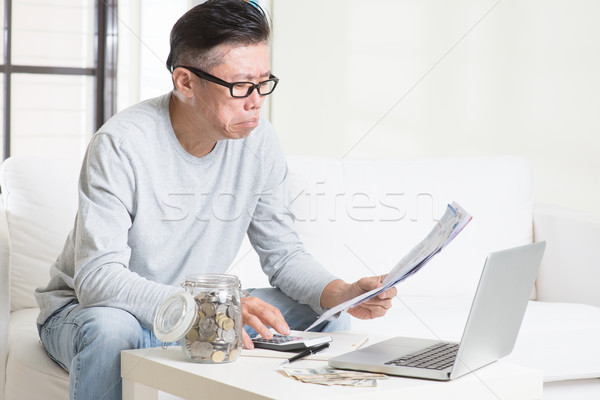 Worried mature Asian man looking at the bills. Stock photo © szefei