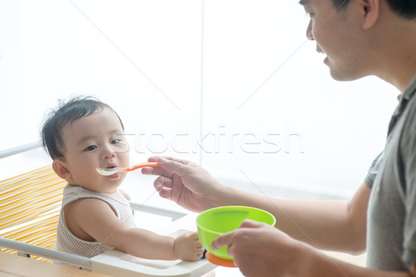 Father feeding toddler food. Stock photo © szefei