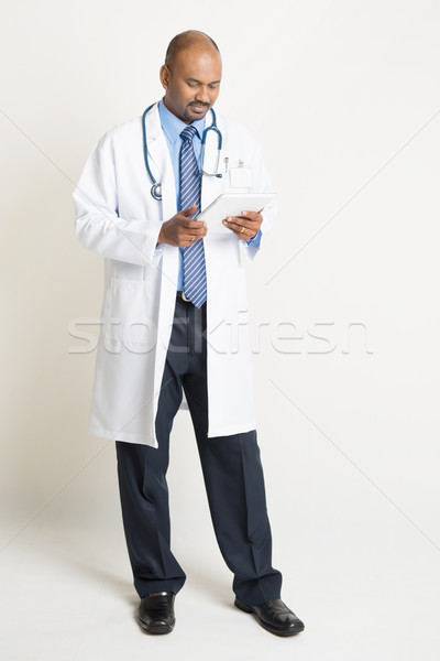 Mature Indian doctor full length using tablet pc Stock photo © szefei