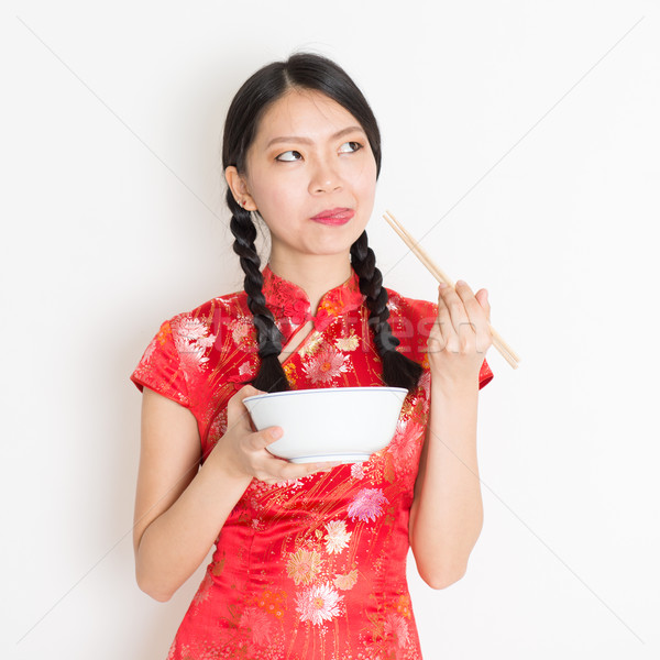 Oriental girl in red qipao eating with chopsticks Stock photo © szefei