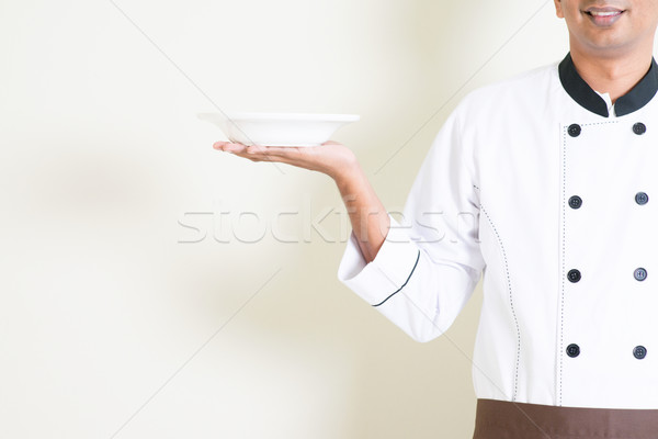 Indian male chef in uniform holding an empty plate Stock photo © szefei