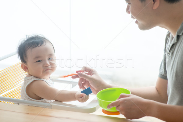 Father feeding toddler solid food. Stock photo © szefei