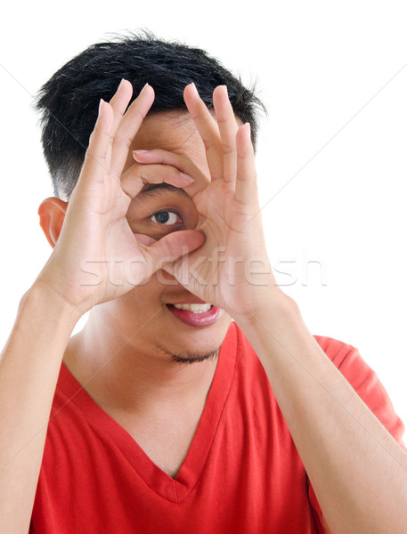 Asian man peeping through fingers hole Stock photo © szefei