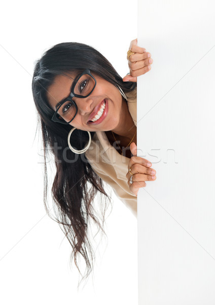 Indian businesswoman peeking from behind blank sign billboard Stock photo © szefei