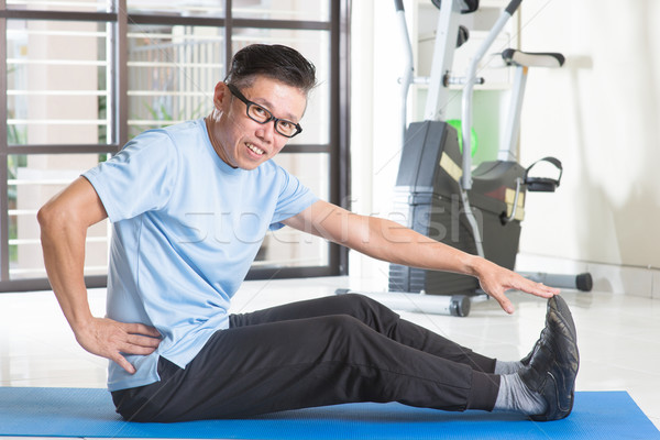 Stock photo: Mature Asian man exercising at gym