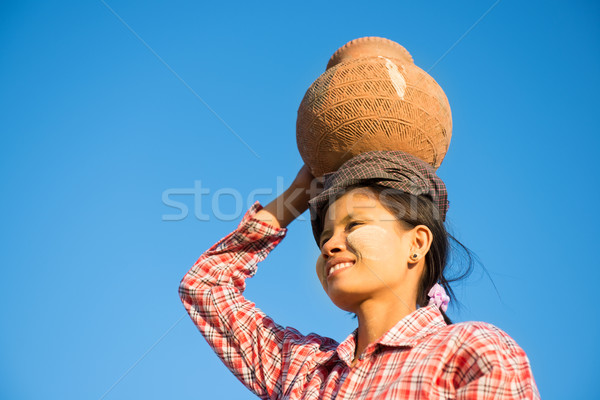 Young Asian traditional farmer carrying clay pot on head Stock photo © szefei