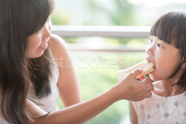Mom feeding child bread Stock photo © szefei