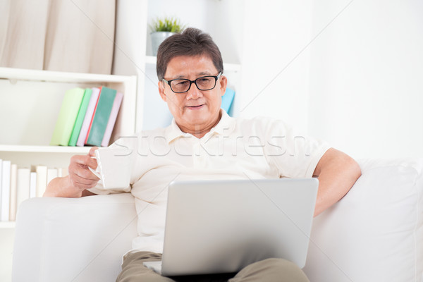 Mature Asian man surfing internet Stock photo © szefei