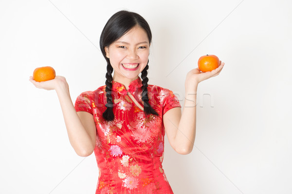Oriental girl in red qipao holding mandarin orange Stock photo © szefei