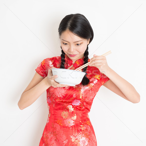 Oriental girl in red cheongsam eating with chopsticks Stock photo © szefei