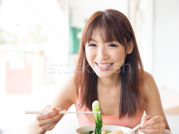 Asian girl eating vegetable noodles Stock photo © szefei